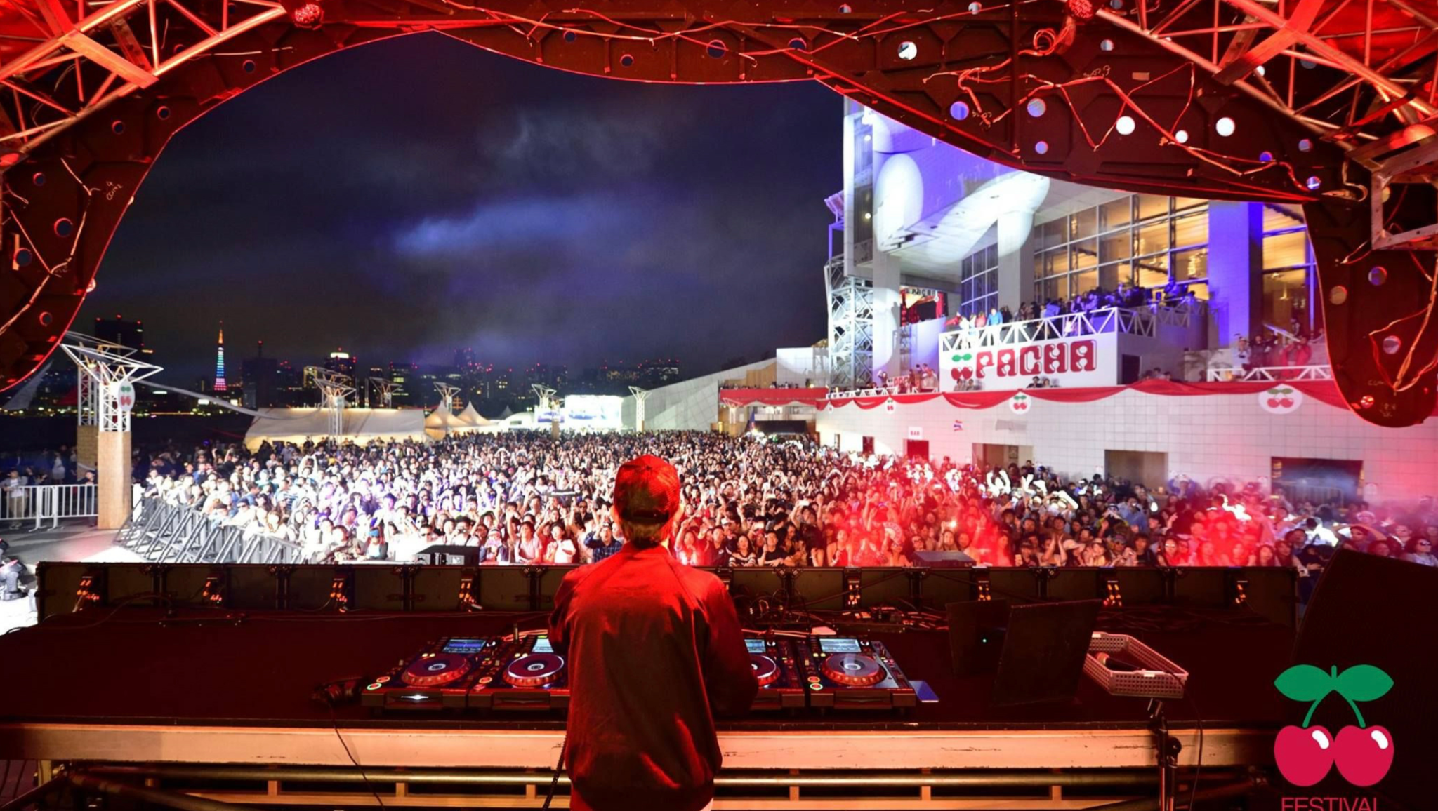 View from behind the DJ booth over a packed Pacha festival audience in Tokyo